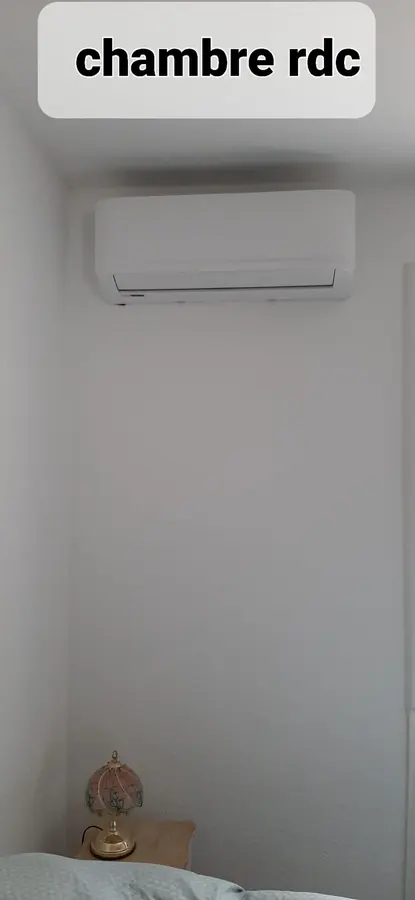 Unité intérieure murale posée au-dessus du lit d'une chambre du rez-de-chaussée.