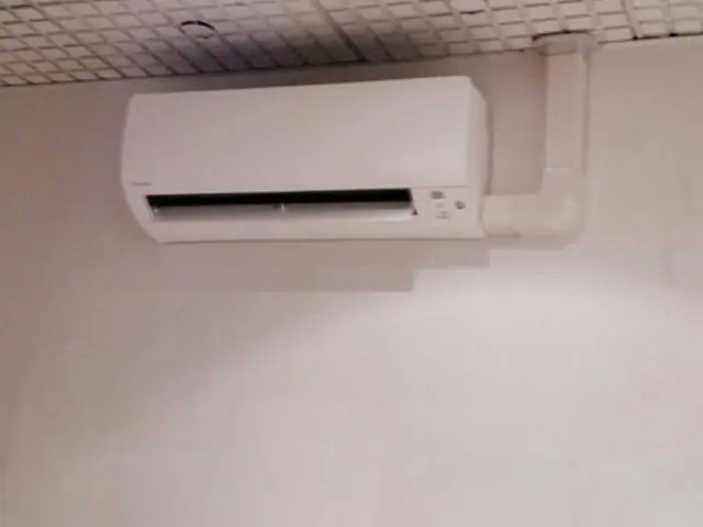 Unité intérieure murale posée sous le faux plafond d'un cabinet dentaire, avec la goulotte de liaison apparente.