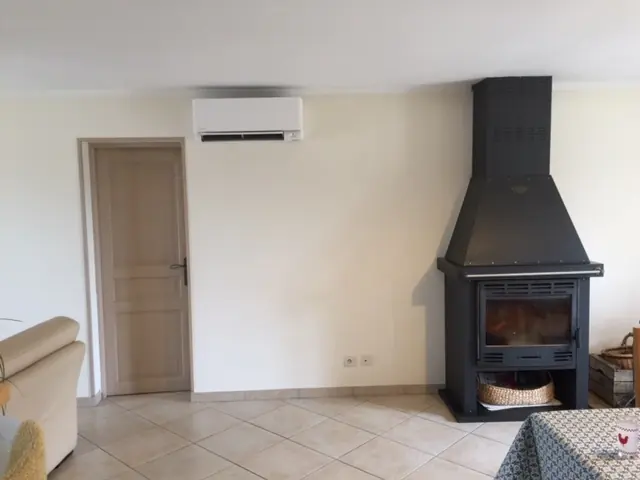 Unité intérieure murale Daikin Stylish posée dans un séjour carrelé, face à la cheminée qu'elle vient compléter.