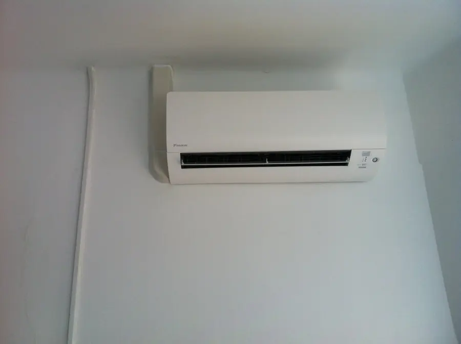 Unité intérieure murale Daikin en fin de pose, alimentation électrique tirée le long du mur.
