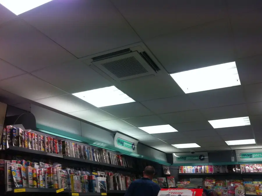 Salle de vente d'un commerce de presse climatisée par une cassette encastrée au plafond, au-dessus des présentoirs.